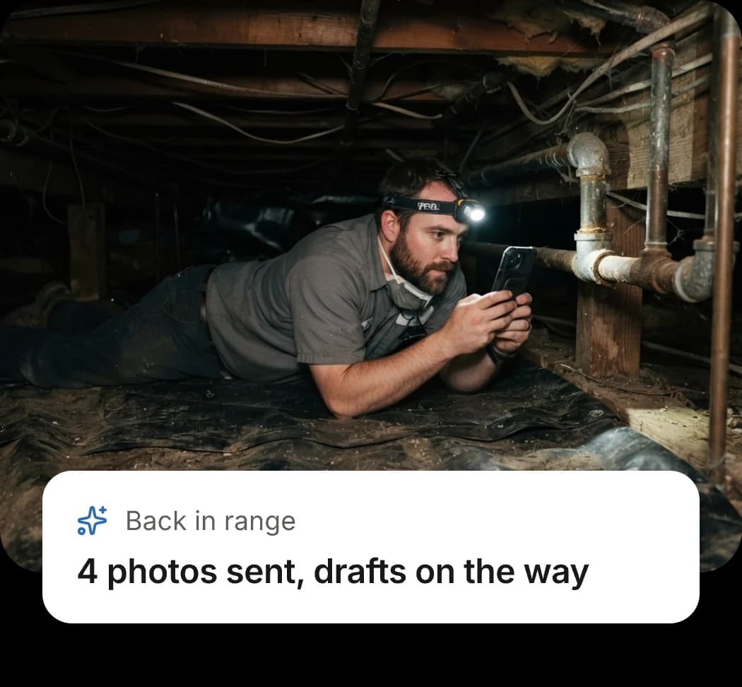 An inspector in a crawlspace with photos waiting to send